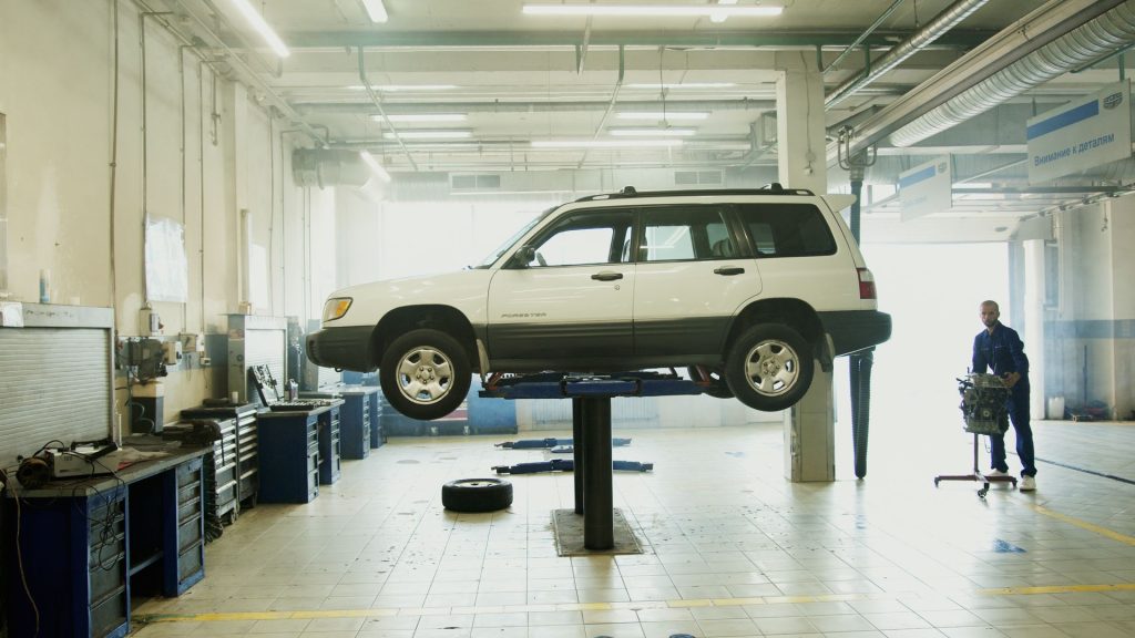 Helle Werkstatthalle mit SUV auf der Hebebühne