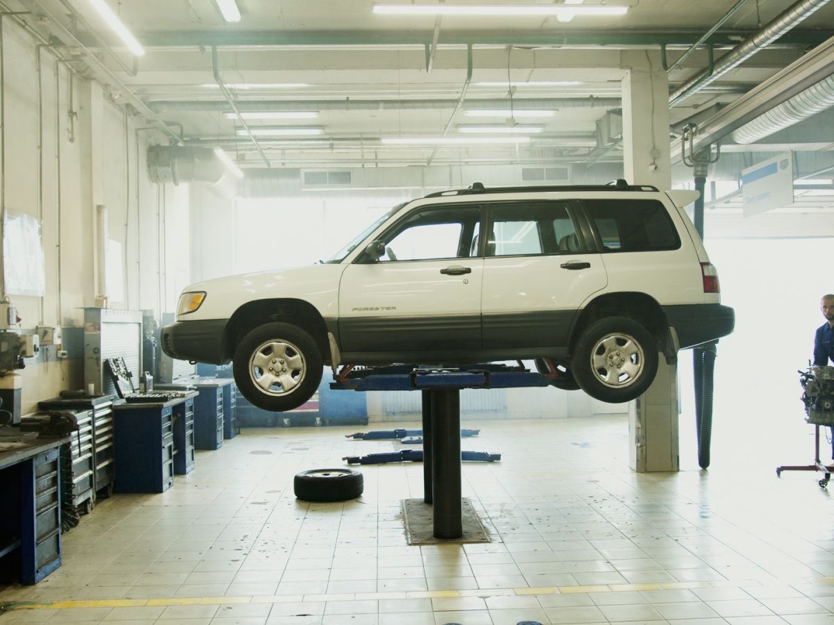 Helle Werkstatthalle mit SUV auf der Hebebühne